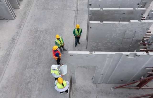 Flat illustration of industrial safety audits in a precast concrete plant, with a supervisor and operator reviewing a mixer lockout point